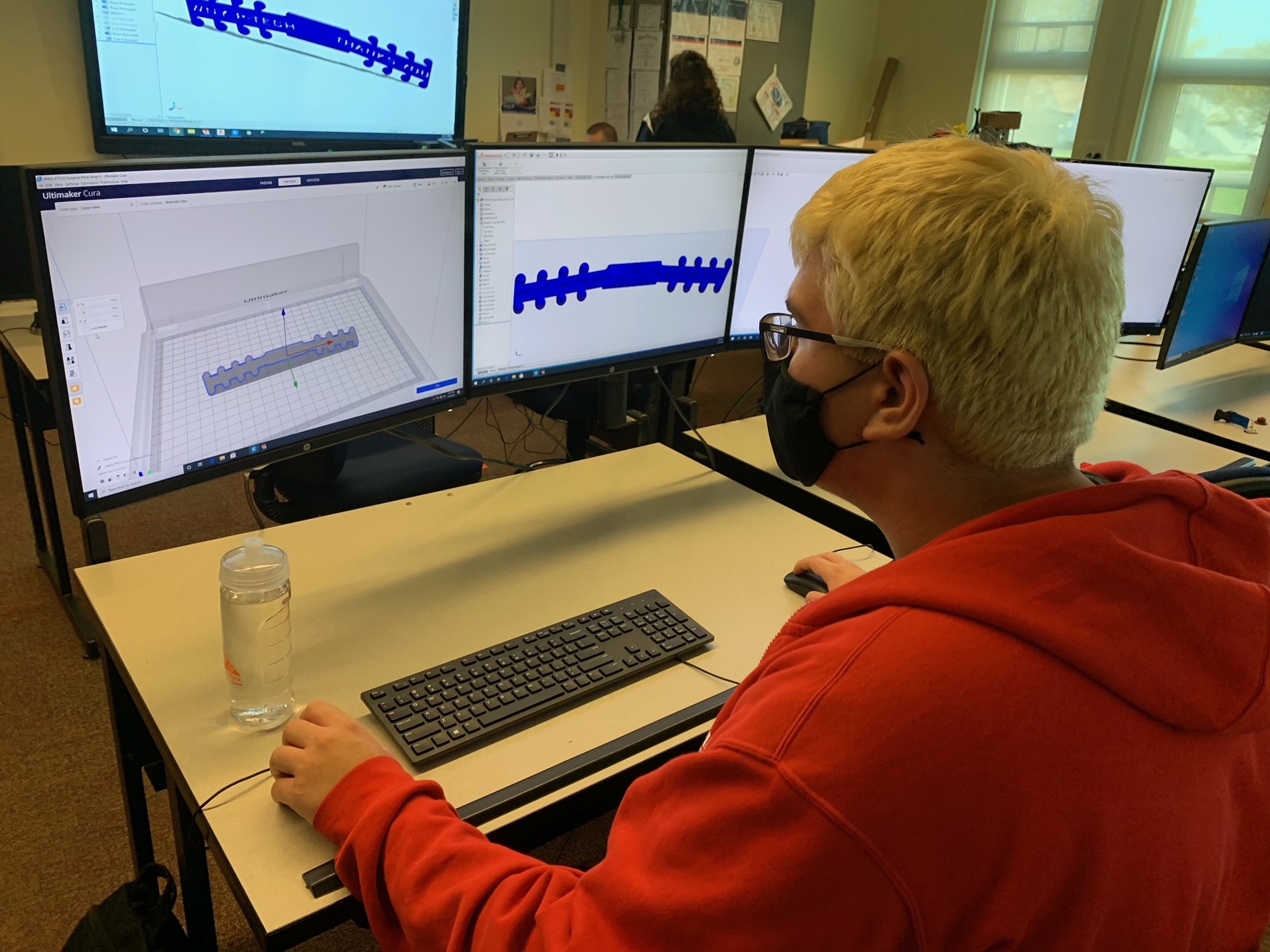 Picture showing a student in front of a computer where we see a 3D development software open with the project for the ear guard